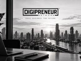 Digipreneur Network logo above a black-and-white city skyline, viewed from a desk with a laptop and notebook