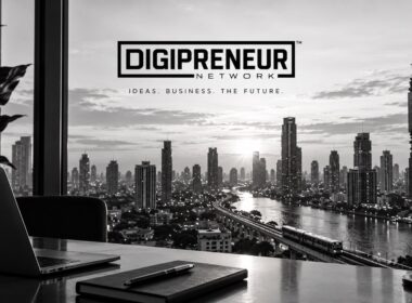 Digipreneur Network logo above a black-and-white city skyline, viewed from a desk with a laptop and notebook
